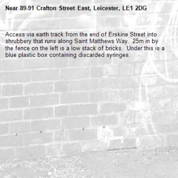 Access via earth track from the end of Erskine Street into shrubbery that runs along Saint Matthews Way.  25m in by the fence on the left is a low stack of bricks.  Under this is a blue plastic box containing discarded syringes.-89-91 Crafton Street East, Leicester, LE1 2DG