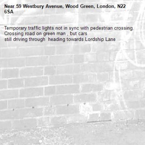 Temporary traffic lights not in sync with pedestrian crossing.  
Crossing road on green man , but cars
still driving through  heading towards Lordship Lane-59 Westbury Avenue, Wood Green, London, N22 6SA