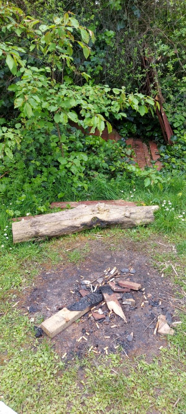 Old wooden fence panels being burned around camp fire in Becton District Park South. Not far from the recently revamped walkway/cycle.-Beckton District Park