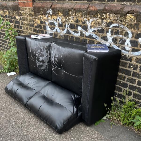 Two black leather sofas, one with two books on it -14 Stanley Street, London, SE8 4BG