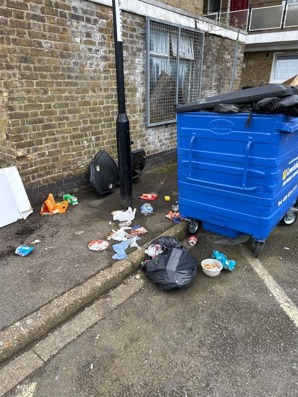 Chairs fly tipped and rubbish scattered around bin with bin bag outside of bin -Dragoon Road, London