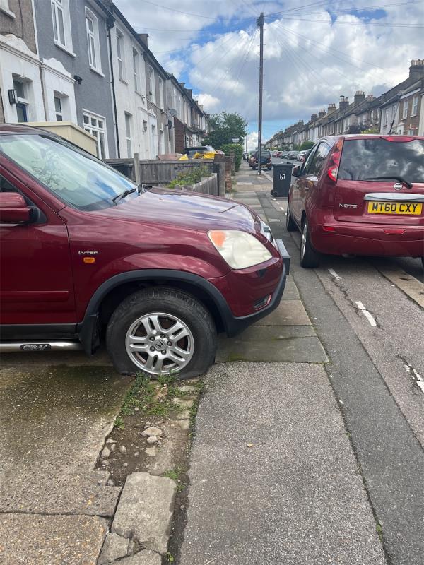 Car with tires down blocking pavement at number 63-63 Sandhurst Road, Catford, London, SE6 1UP