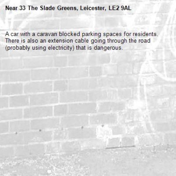 A car with a caravan blocked parking spaces for residents. There is also an extension cable going through the road (probably using electricity) that is dangerous.-33 The Slade Greens, Leicester, LE2 9AL