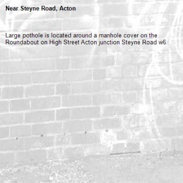 Large pothole is located around a manhole cover on the Roundabout on High Street Acton junction Steyne Road w6 -Steyne Road, Acton