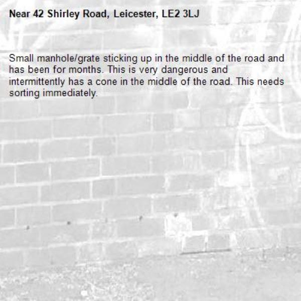 Small manhole/grate sticking up in the middle of the road and has been for months. This is very dangerous and intermittently has a cone in the middle of the road. This needs sorting immediately.-42 Shirley Road, Leicester, LE2 3LJ