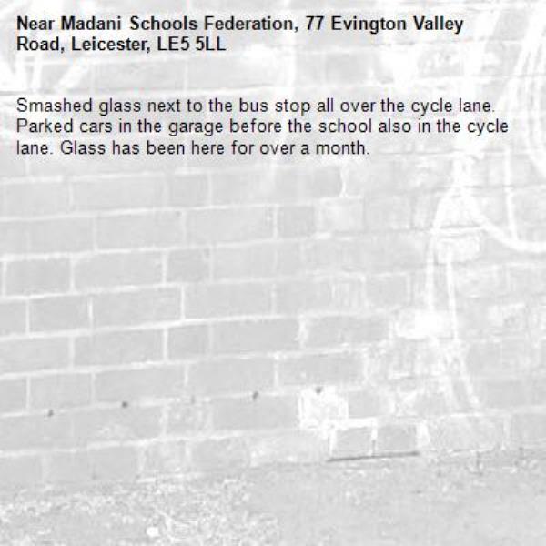 Smashed glass next to the bus stop all over the cycle lane. Parked cars in the garage before the school also in the cycle lane. Glass has been here for over a month.-Madani Schools Federation, 77 Evington Valley Road, Leicester, LE5 5LL