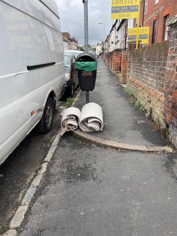 underneath the litter bin outside of four Zinzan Street. DIY or construction waste in terms of rolled up carpet. This has been put there since yesterday evening.-A, 4 Zinzan Street, Reading, RG1 7UQ