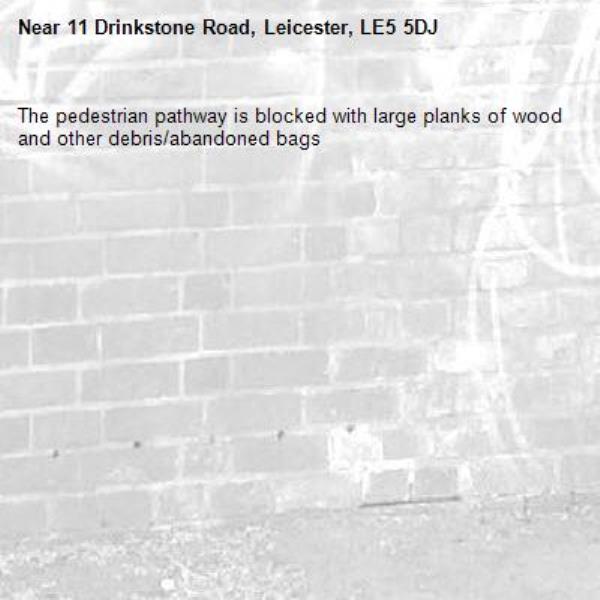 The pedestrian pathway is blocked with large planks of wood and other debris/abandoned bags-11 Drinkstone Road, Leicester, LE5 5DJ