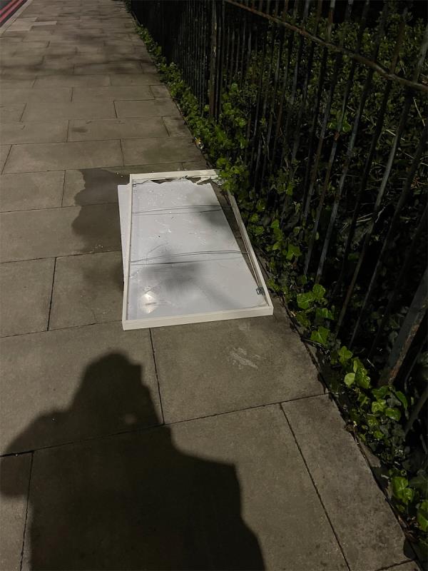 Some sort of door or panel in pavement causing trip hazard. BROKEN GLASS! Please remove asap as this may cause injury -Pier Road, North Woolwich, London