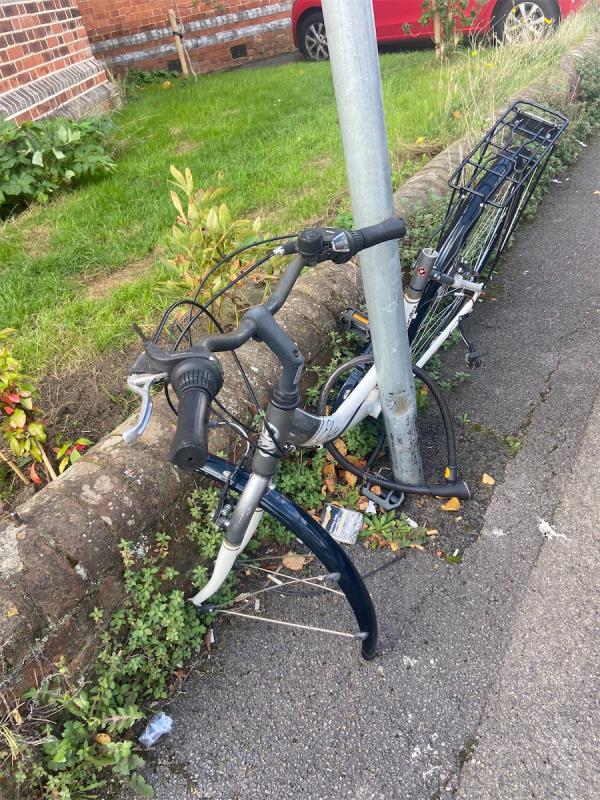 Bike abandoned and stripped of parts, locked to post opposite the barbers-97 Donnington Road, Reading, RG1 5NE