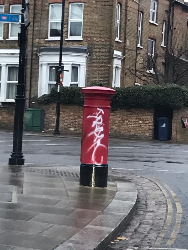 White spray painted tag is located on a red Royal Mail post box on Loveday Road junction Churchfield Road W13-Adam House Loveday Road, West Ealing, W13 9JT