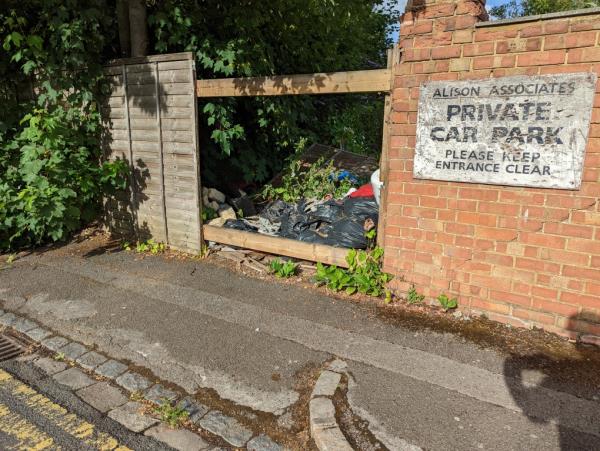 Increasingly big pile of rubbish shoved through broken fence and starting to litter the road-20 Kingsgate Street, Reading, RG1 3JR