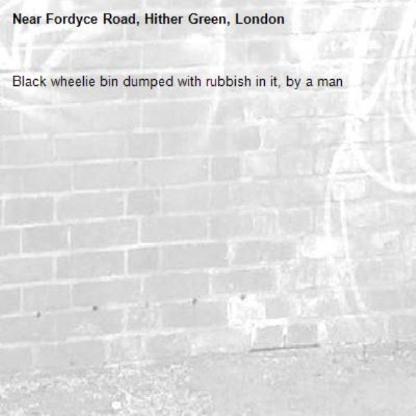 Black wheelie bin dumped with rubbish in it, by a man -Fordyce Road, Hither Green, London