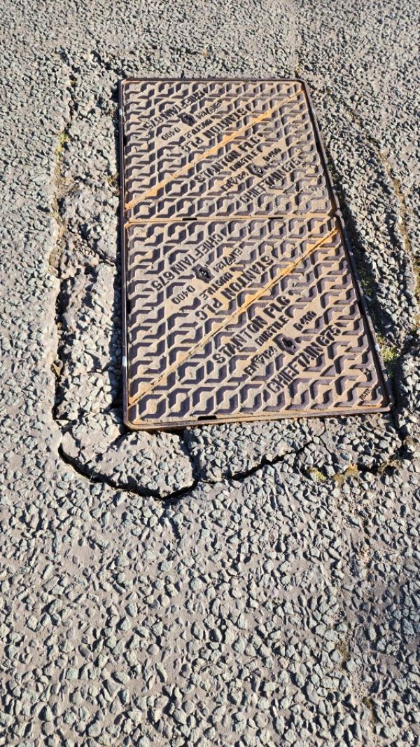 Manhole sinking in. Dangerous for cars and pedestrians. Makes loud noises when cars go over it -33 Herongate Road, Thurnby Lodge, LE5 0AW, England, United Kingdom