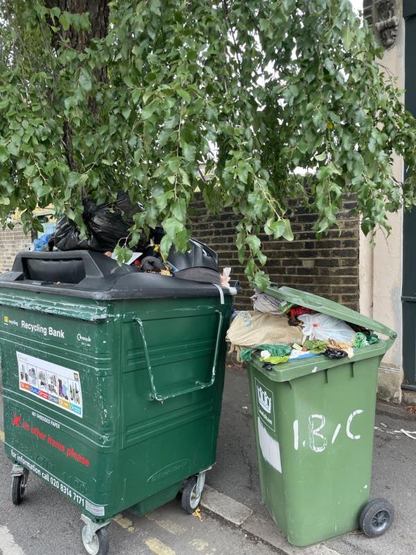 Large wheelie bin (commercial / communal recycling) and a normal sized recycling wheelie bin. Not associated with any of the nearby properties. Overflowing with rubbish, spilling on to pavement. Been here for weeks. -Heathfield Court, Avonley Road, London, SE14 5AP