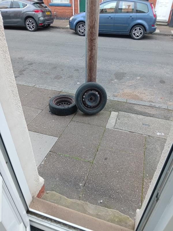Still there despite being reported one week ago!! - two old car tyres/wheels outside my house. Please remove ASAP please - also pedestrian hazard. -24 Raymond Road, Leicester, LE3 2AS