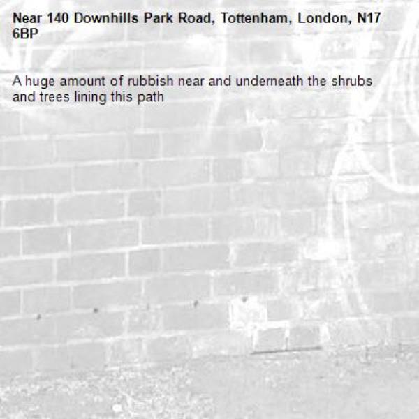 A huge amount of rubbish near and underneath the shrubs and trees lining this path-140 Downhills Park Road, Tottenham, London, N17 6BP