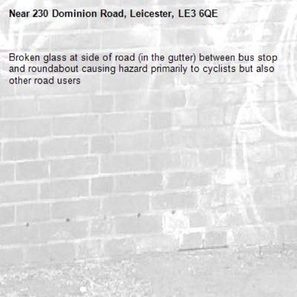 Broken glass at side of road (in the gutter) between bus stop and roundabout causing hazard primarily to cyclists but also other road users -230 Dominion Road, Leicester, LE3 6QE