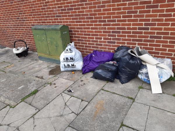 A baby carseat Bags of wastes and clothing dumped near block 71-79 Garvary Road E16 -69 Garvary Road, Canning Town, London, E16 3NG