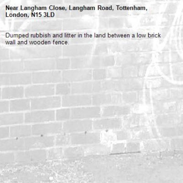 Dumped rubbish and litter in the land between a low brick wall and wooden fence.-Langham Close, Langham Road, Tottenham, London, N15 3LD
