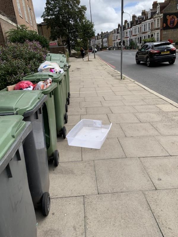 Bins overflowing near to busy Lee High Rd. Wind blowing detritus into main road -Manor Park Parade, Lee High Road, London, SE13 5PB